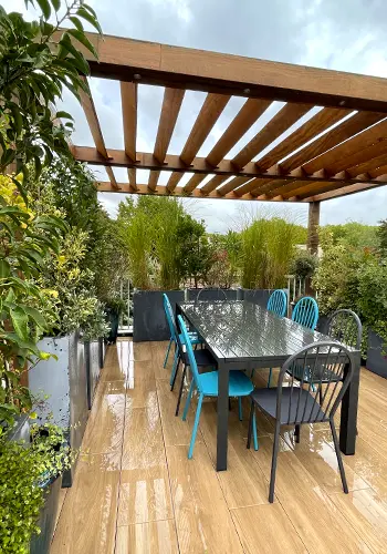 Terrasse en région Parisienne avec une pergola en bois exotique et mobilier d'extérieur