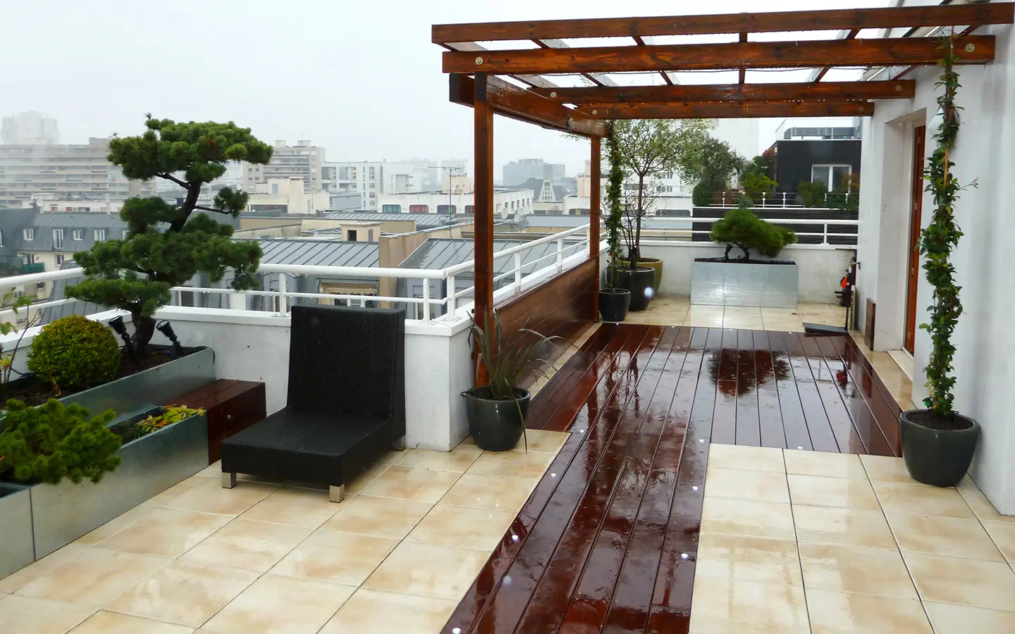 Dans le 19ème arrondissement de Paris, terrasse minimaliste zen mêlant le bois l’aluminium, le dallage et des poteries sobres.